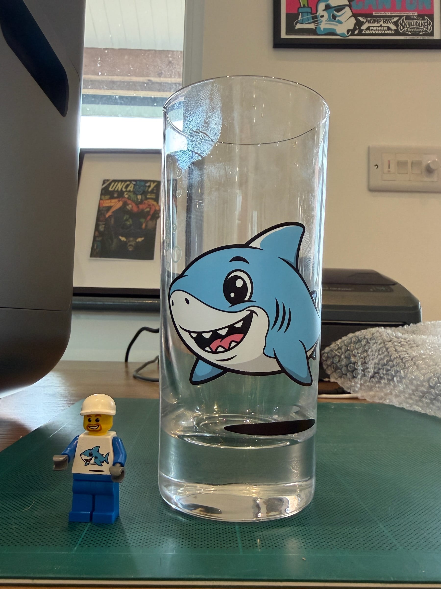 Clear glass with cartoon shark design beside LEGO minifigure