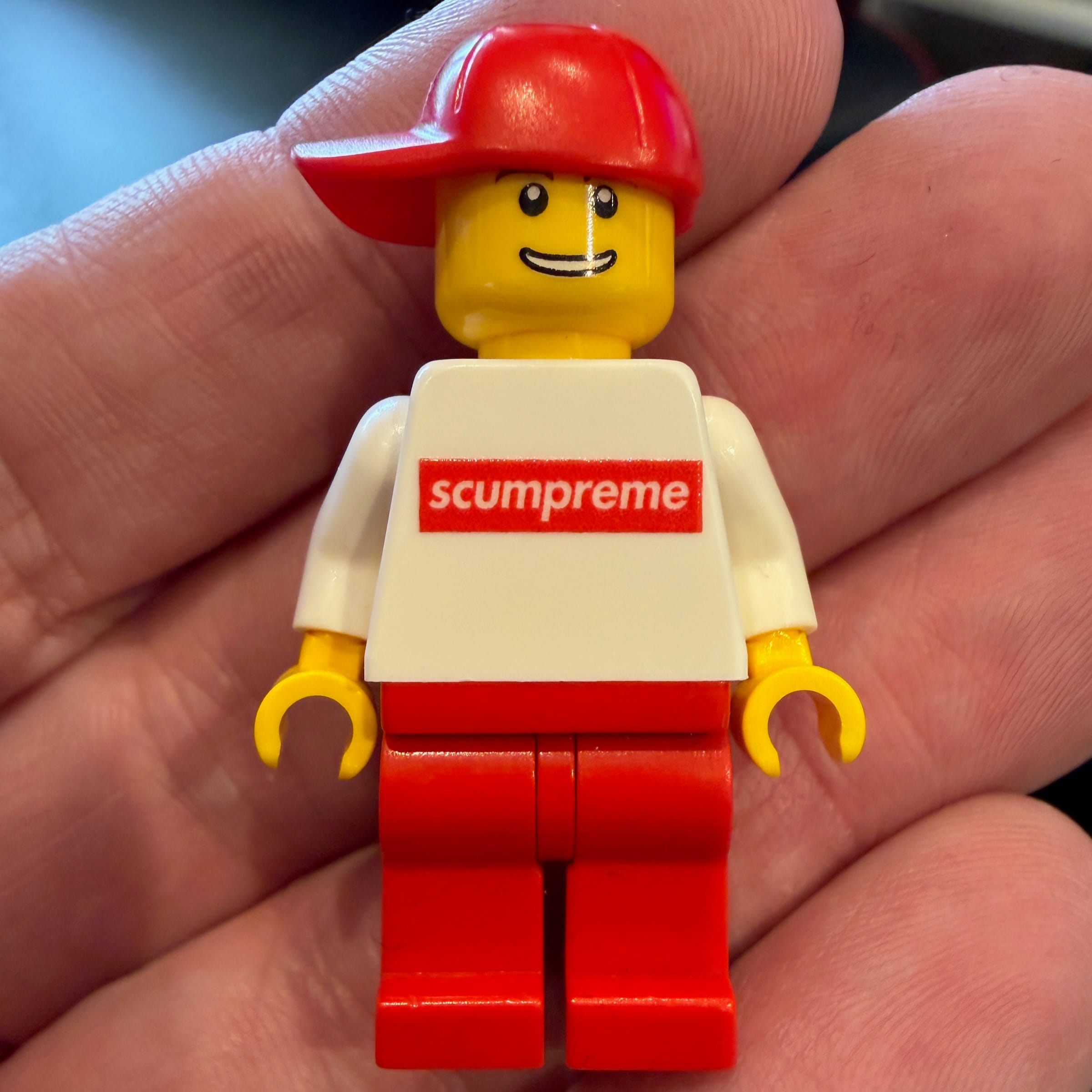 LEGO minifigure wearing Supreme-style branded clothing held in hand