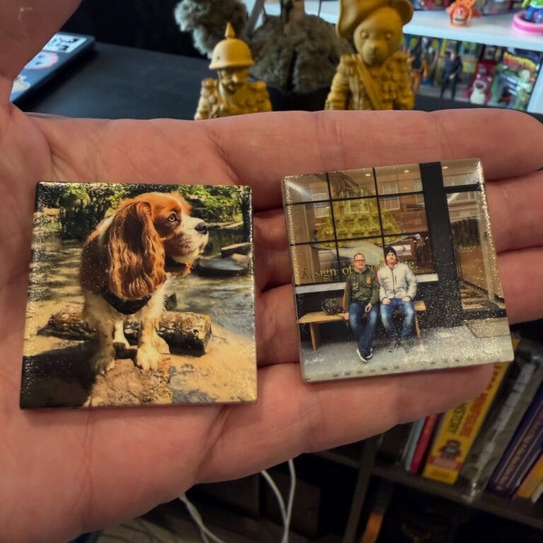 Hand holding two small photo prints of dog and people
