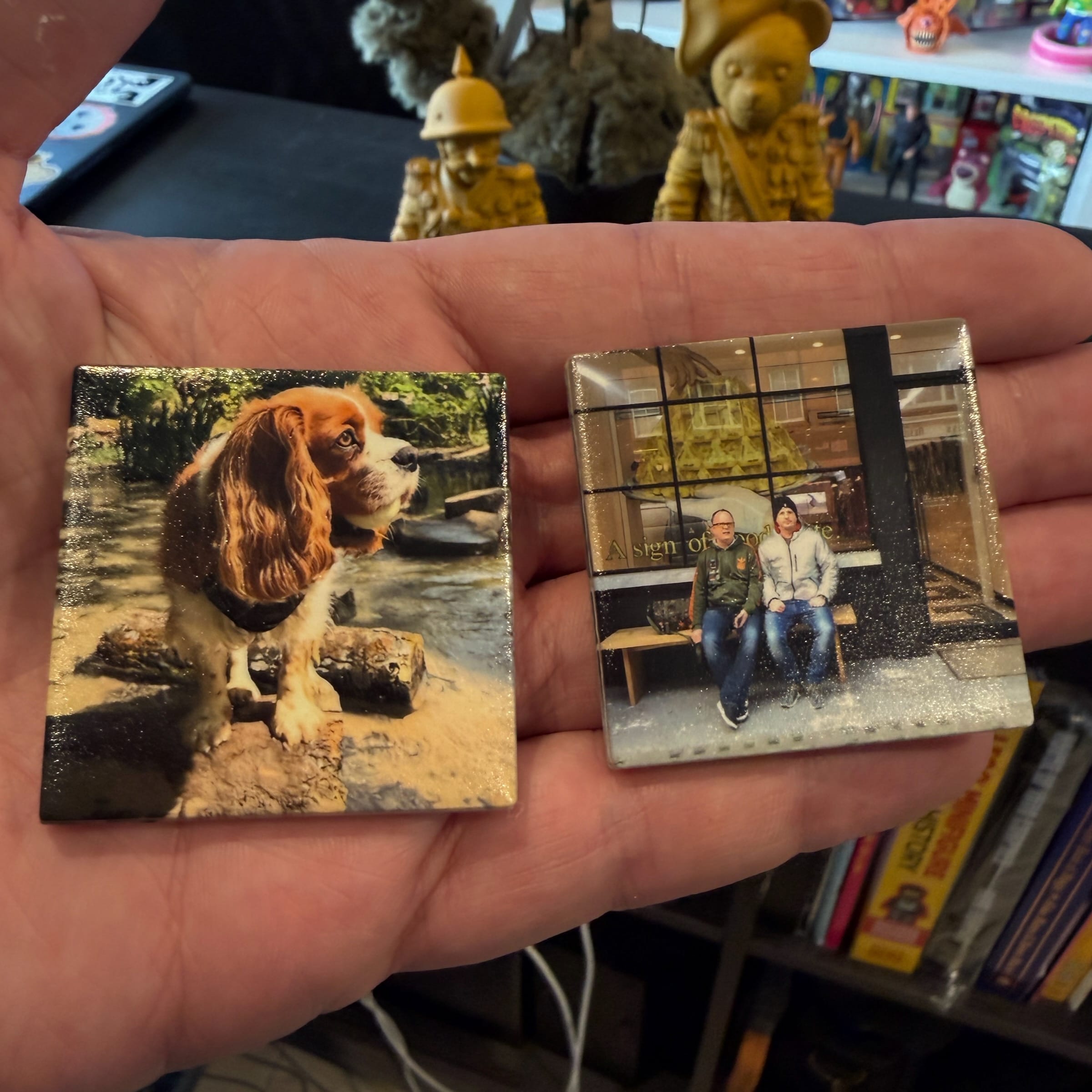 Hand holding two small photo prints of dog and people